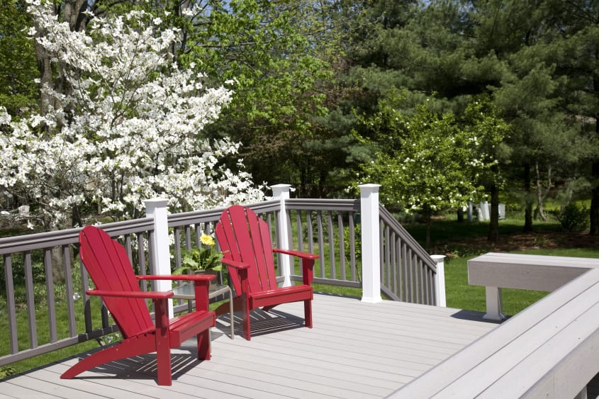 Pale gray wood deck with rail and two wood Adirondak red chairs