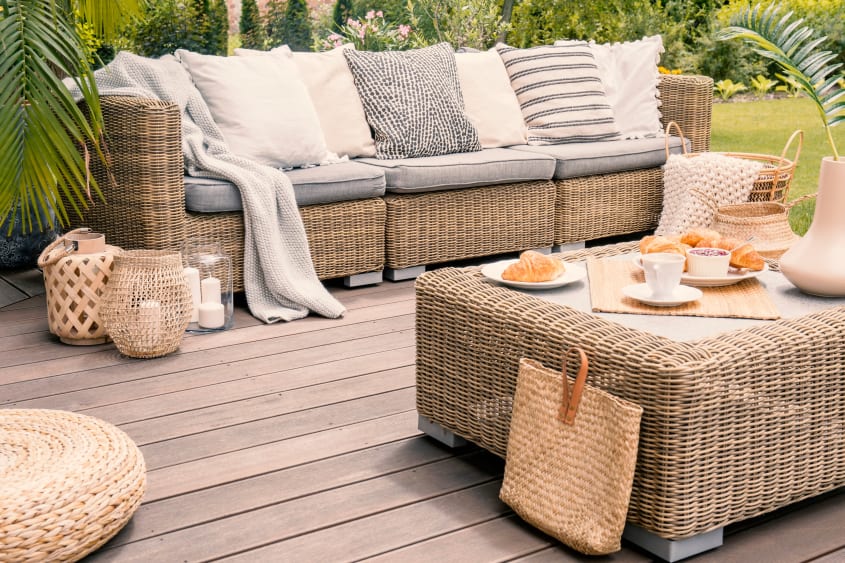 Outdoor deck with wicker patio furniture, beige cushions and breakfast on the table