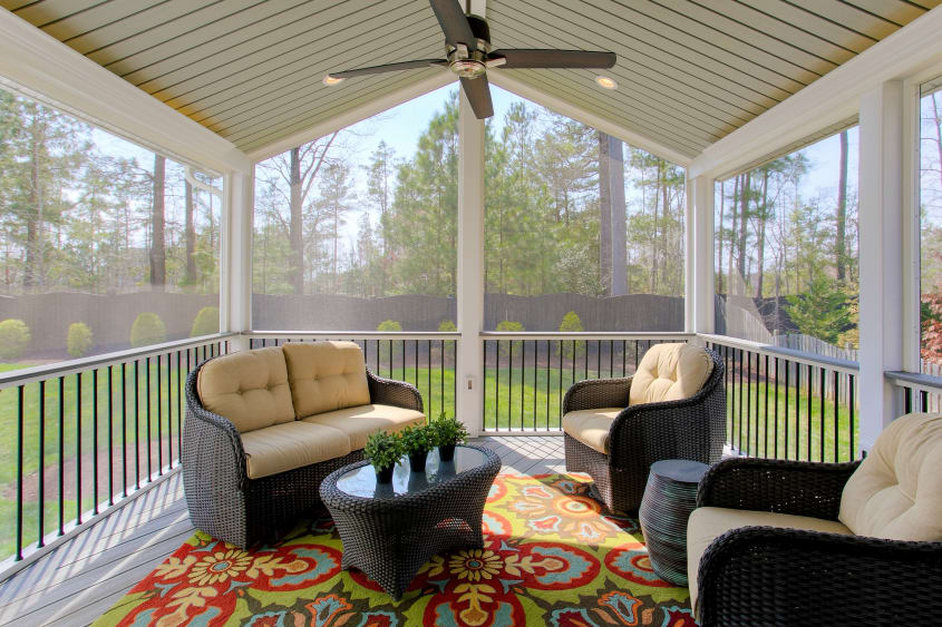 Covered screened deck with comfortable seating, overhead fan and colourful carpet