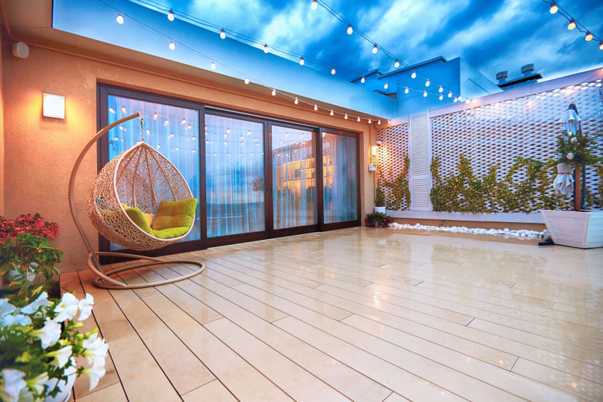 Clean wood deck with hanging egg chair and overhead string lights