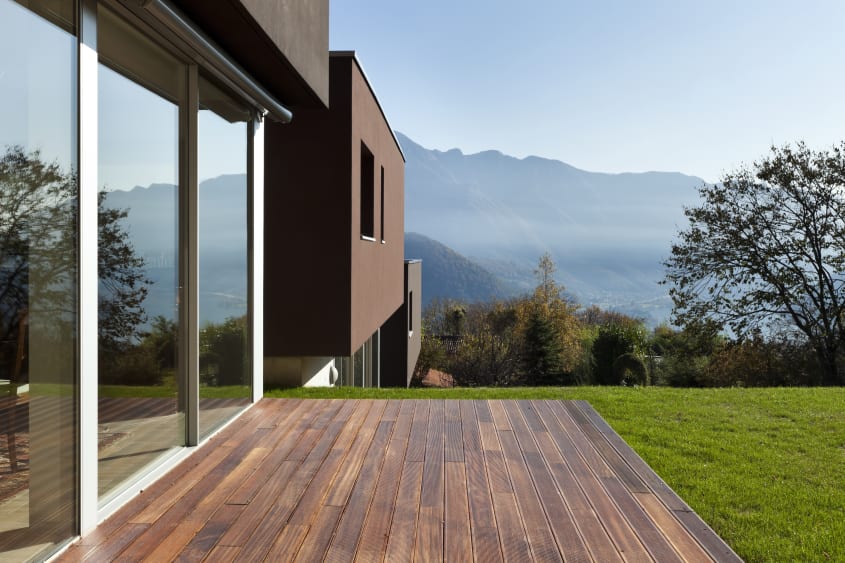 Modern house on a mountainside with sleek dark wood patio and grass