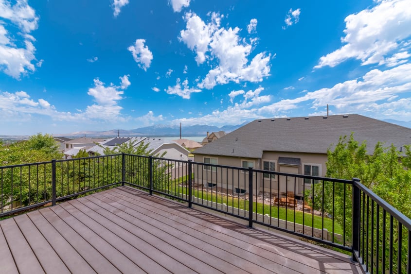 Upper level brown wood deck featuring a black iron railing