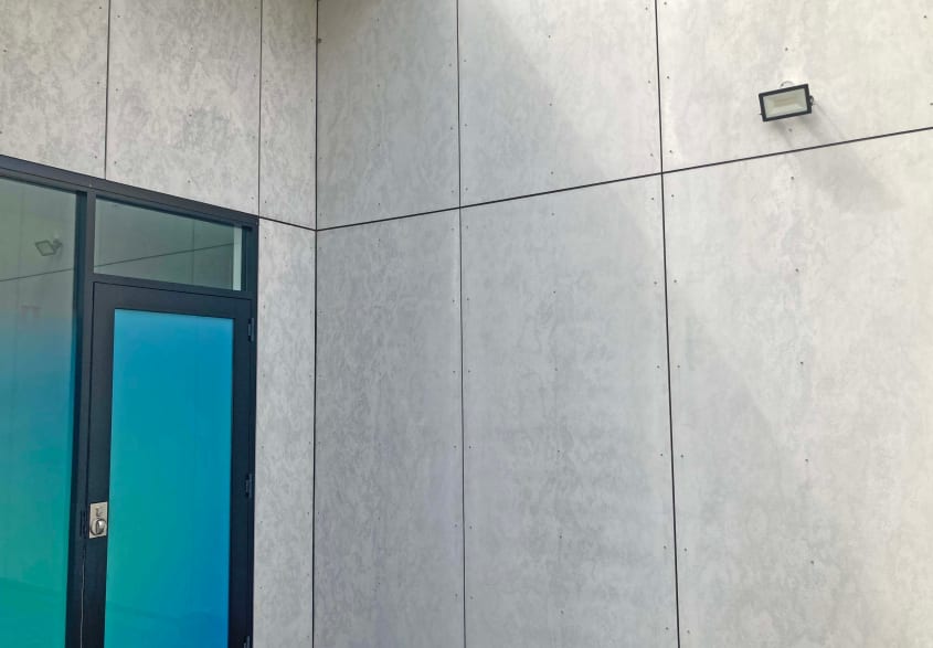 Grey house exterior with fibre cement siding and blue and black door