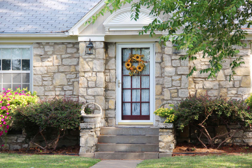 Close up of light-coloured stone house with a glass door