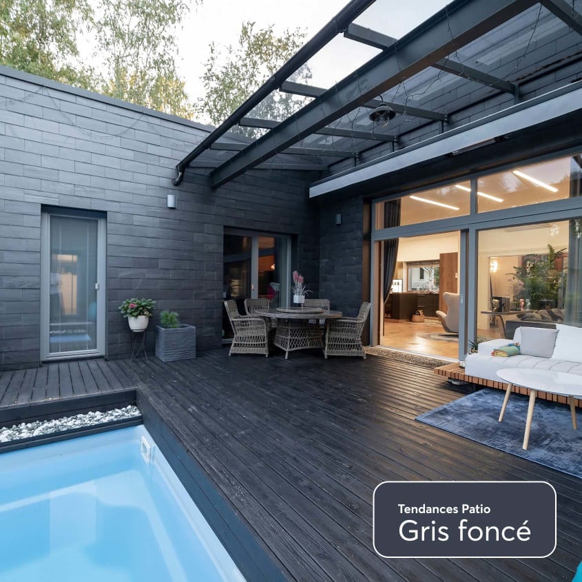 Cour arrière d’une maison contemporaine avec revêtement de maison et de patio gris foncé.
