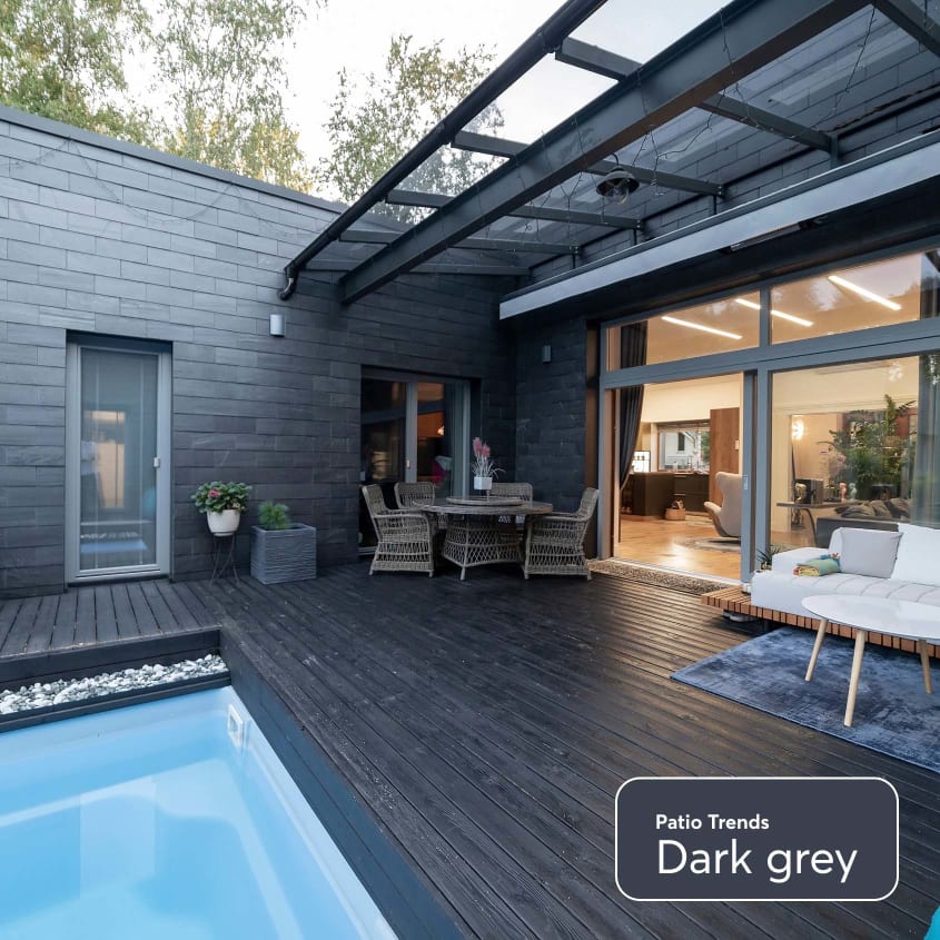 Backyard of a contemporary home with dark grey exterior siding and patio.