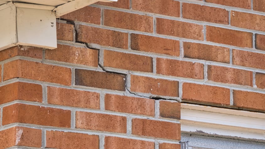 Mur extérieur fissuré d’une maison en briques