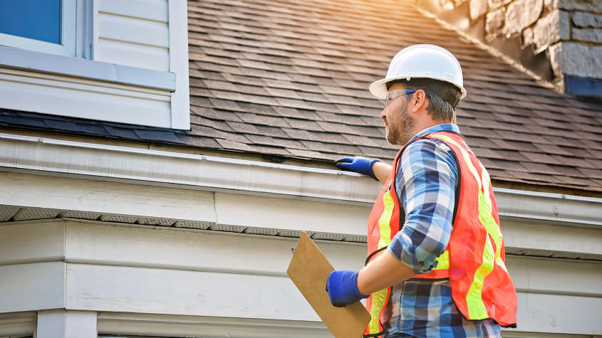 Couvreur avec équipement qui inspecte le toit d’une propriété