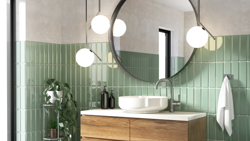Lavabo blanc, miroir rond, mur recouvert de carreaux vert sauge, meuble en bois et luminaires sphériques