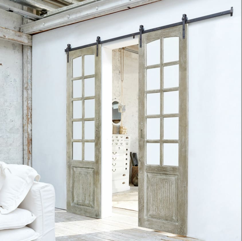 Portes de grange coulissantes en bois patiné, séparant deux pièces dans un espace de style loft
