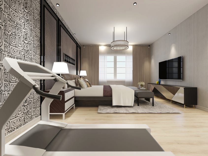 Chambre spacieuse avec grand lit, ottoman, commode, écran télé au mur et tapis roulant