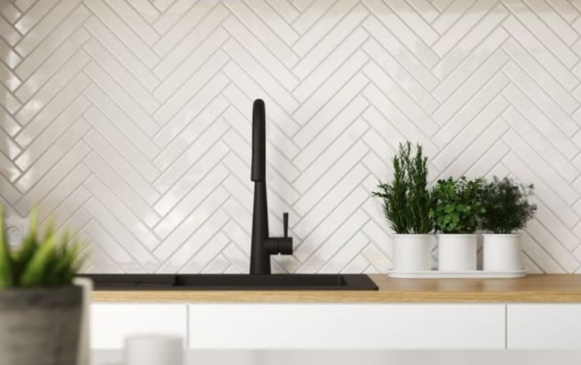 white herringbone backsplash tile behind wooden counter and black sink