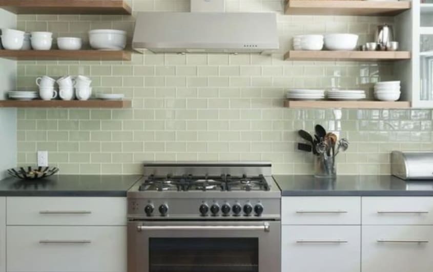 kitchen with exposed wooden tablets, green glass backsplash, and white cabinets