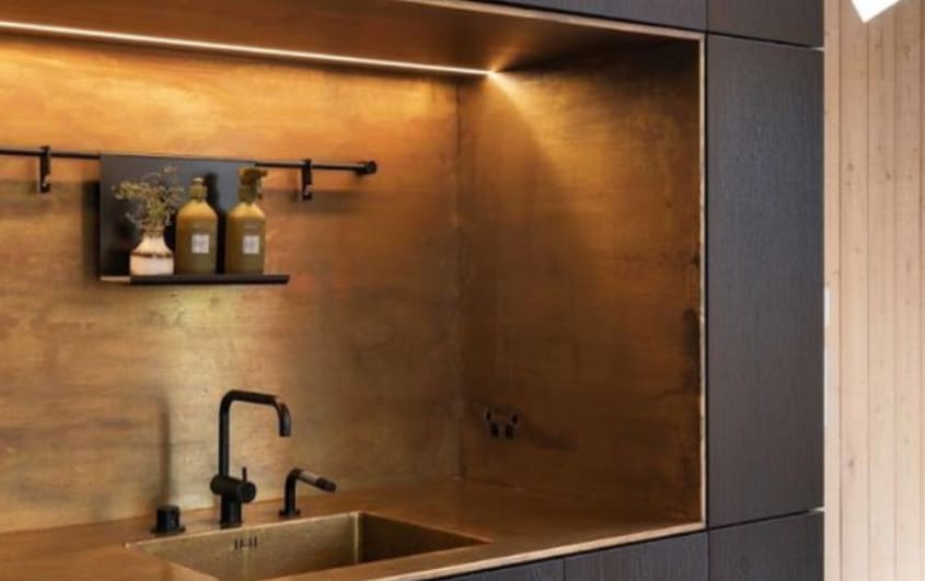 Black kitchen with copper backsplash alcove for sink