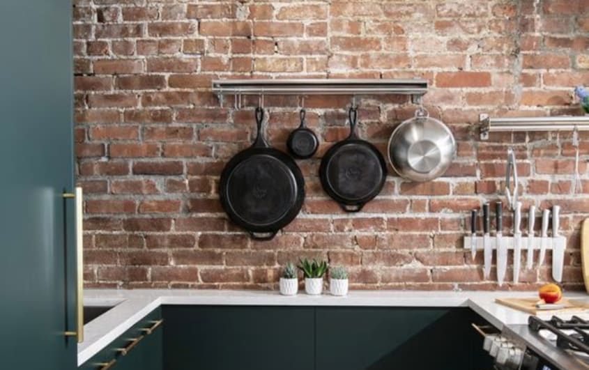 black kitchen with exposed red brick as a backsplash
