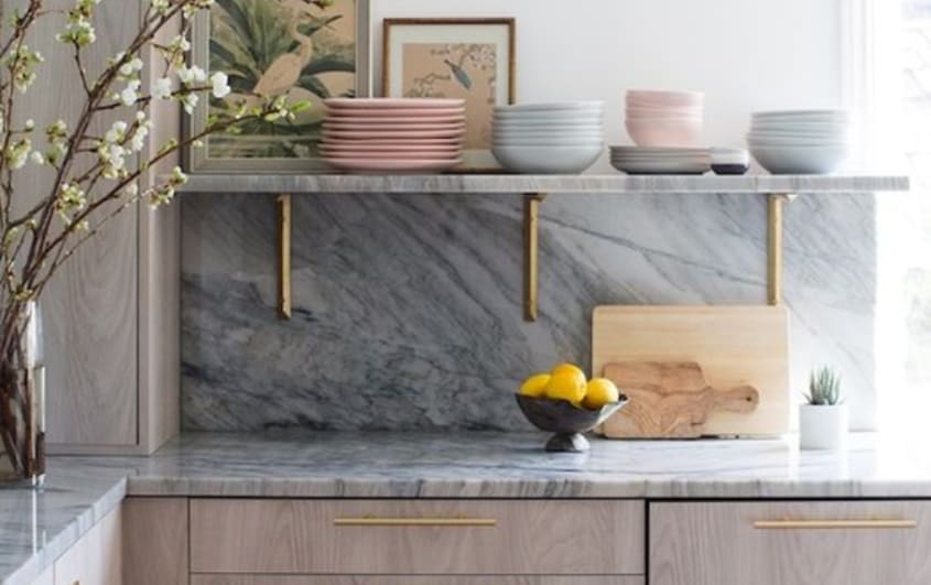 Grey stone backsplash and counter in kitchen with wood cabinets