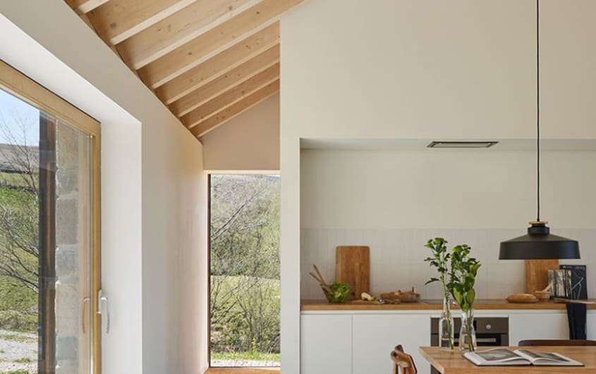 White kitchen with added section to the left with exposed wood beams