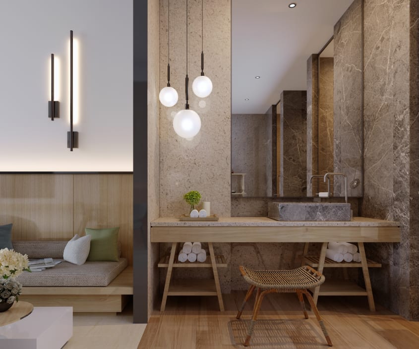Dans une salle de bain luxueuse de style japandi, une alcôve à mur en marbre, travertin et grand miroir, dans laquelle est encastrée un meuble-lavabo en bois et comptoir de travertin sur tréteaux, vasque en marbre veiné gris, petit banc en rotin, trois su