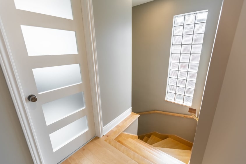escalier en bois pâle avec porte moderne vitrée et fenêtre