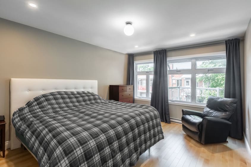 chambre à coucher avec couvre-lit carreauté gris et fauteuil en cuir noir