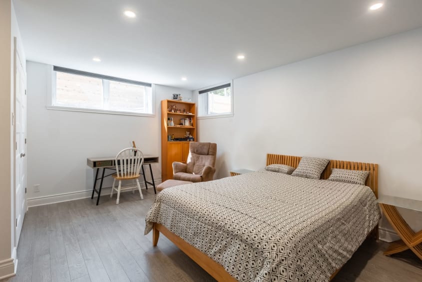 chambre au sous-sol avec lit et étagère en bois, table et chaise