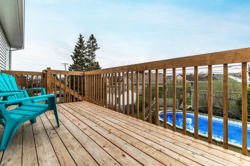 Balcon arrière en bois au deuxième étage avec chaises turquoise et vue sur piscine hors-terre