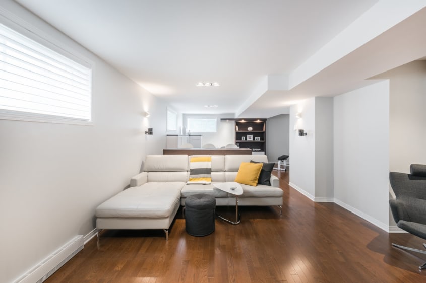 rénovation d'un sous-sol de style contemporain avec divant beige et plancher de bois franc