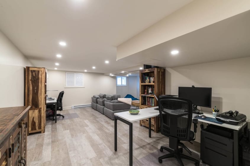 Rénovation d'un sous-sol moderne avec coin bureau et plancher en bois flottant gris pâle