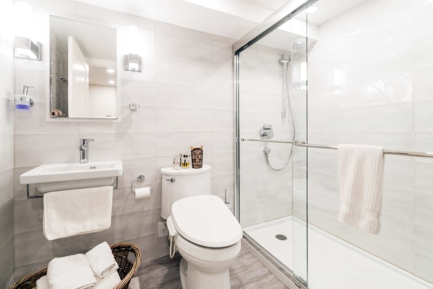 Salle de bain moderne d'un sous-sol rénovée avec lavabo blanc autoportant et bain-douche