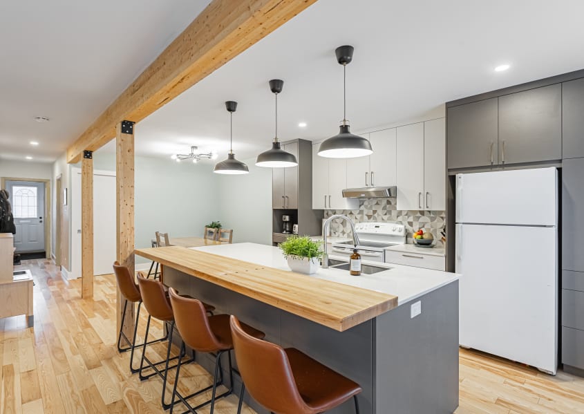 cuisine à aire ouverte avec cabinets deux tons, grand îlot et poutres en bois