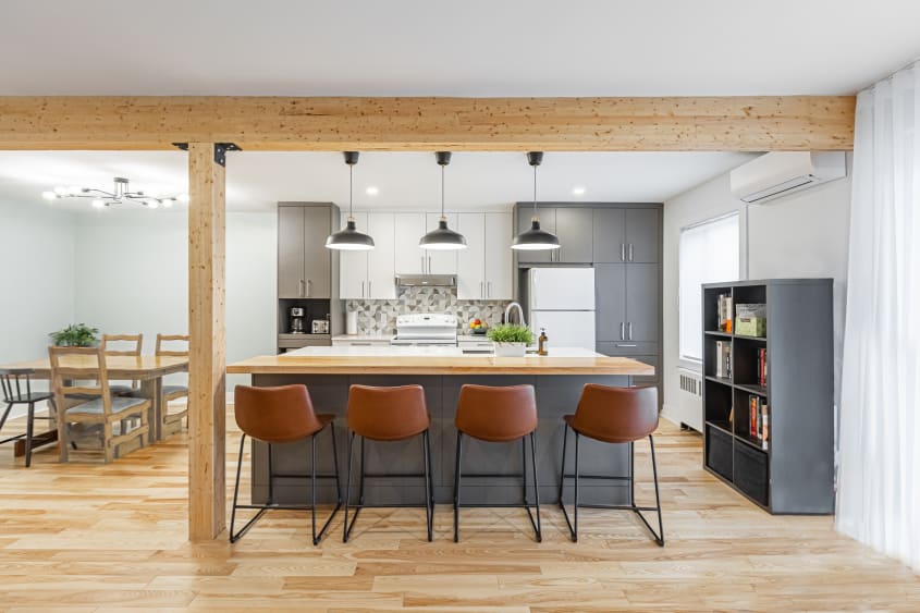 cuisine à aire ouverte avec comptoirs en quartz blanc avec une section en bois sur l'îlot