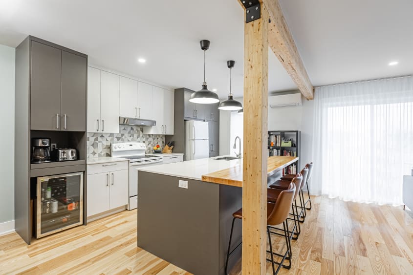 grand îlot dans une cuisine à aire ouverte moderne avec armoires blanches et grises