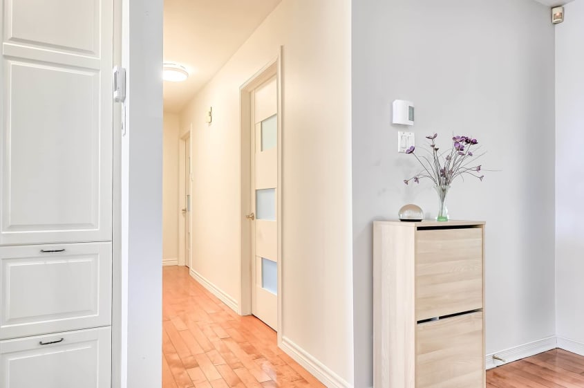 portes vitrées blanches dans passage avec plancher en bois franc et commode blanche