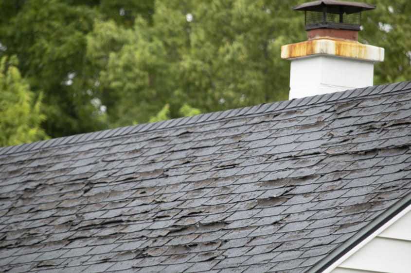 Roof with rusted chimney and damaged shingles