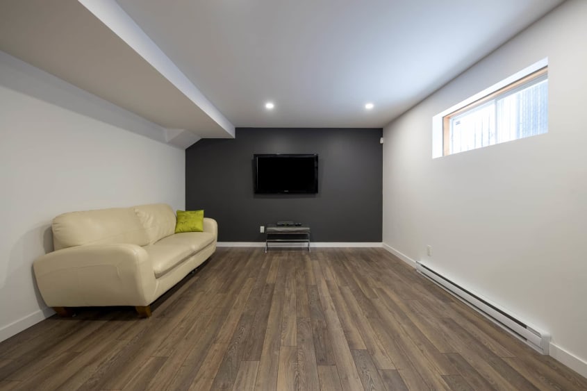 Rénovation de sous-sol avec plancher en bois flottant avec espace télé.