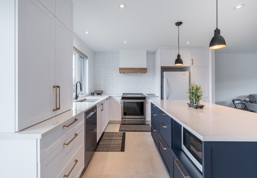 Renovated modern kitchen with large center island, white cabinets, and rectangular sand colored ceramic tiles