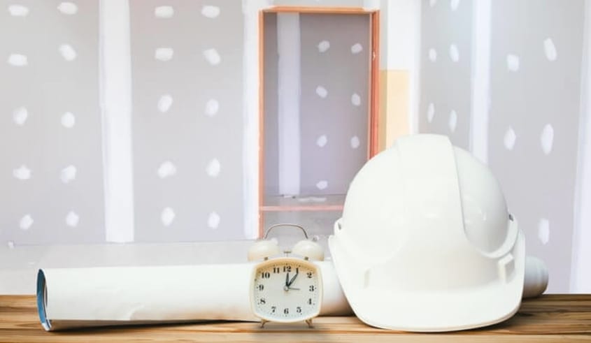 Casque blanc de construction avec cadran et plans sur un chantier de rénovation